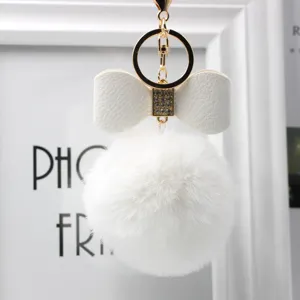White faux fur pom pom keychain with elegant leather bow and gold hardware charm.