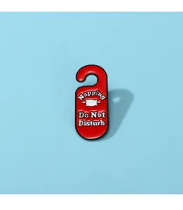 Primo piano dettagliato della spilla smaltata rossa con cuscino e design giocoso.