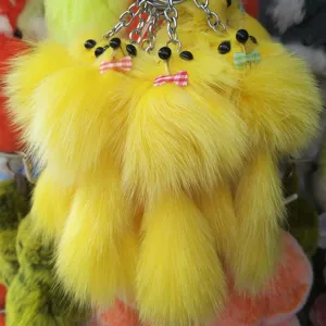Close up detail of yellow fluffy fur pom pom keychain with cute bow and bead eyes charm.