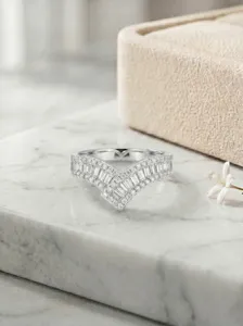 Gedetailleerde opname van asymmetrische V-vormige zilveren ring met baguettewitte stenen.