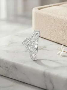 Detailopname van de asymmetrische V-zilveren ring met baguette en ronde stenen.