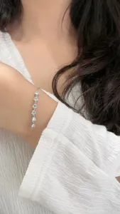 Nahaufnahme eines zarten silbernen Armbands, das elegant am Handgelenk glitzert.