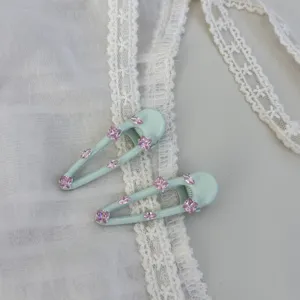 Minzgrüne Haarklammer im Detail mit funkelnden rosa Zirkoniasteinen für elegantes Seitenstyling.