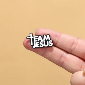 Detail shot of black and white enamel alloy brooch with Team Jesus letter design for clothing.