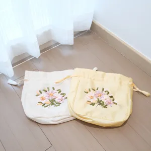 Handmade silk drawstring pouch with delicate floral ribbon embroidery detail for vintage wear.