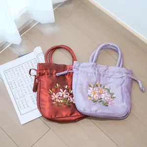 Traditional Chinese silk embroidered handbag with ribbon flowers and drawstring detail view.