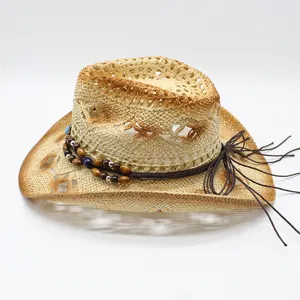 Gros plan du chapeau de cowboy en paille ajouré avec perles en bois et glands en cuir.