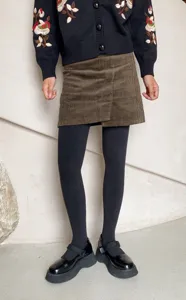 Detail shot of winter fleece-lined dark gray tights paired with chic skirt and platform shoes.