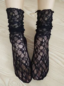 Detail view of sheer black lace ruffle socks, vintage hollow mesh mid-calf stack socks.