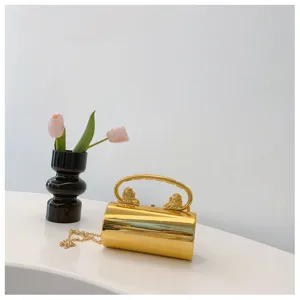 Goldene Acryl Zylinder Abendtasche mit schickem Löwenkopf Griff und eleganter Kette.