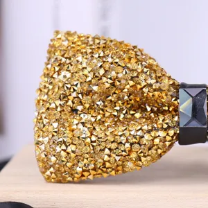 Close-up detail of luxury gold rhinestone bow tie with sparkling crystals and black center stone.