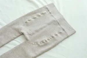 Close-up detail of thermal ribbed knit tights in oatmeal beige, soft fleece lined texture.