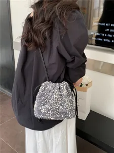 Vue détaillée d'un sac seau à sequins élégant avec cordon de serrage doux et finition brillante.