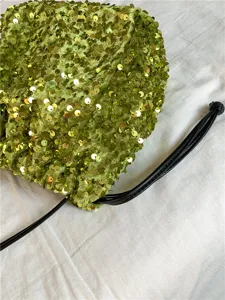 Détail de sac bandoulière à sequins verts, avec pochette plissée douce et cordon noir.