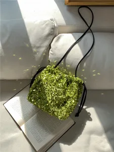 Gros plan d'un sac seau étincelant en sequins verts avec cordon de serrage et bandoulière.