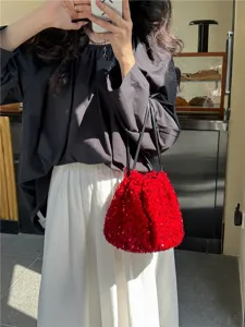 Sac seau rouge à sequins, détail montrant texture brillante, fermeture cordon et bandoulière chic.