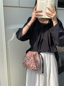 Vue rapprochée du sac seau à sequins roses, sac bandoulière souple avec finition pailletée.
