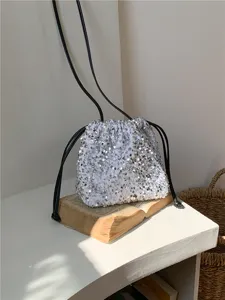 Détail de gros plan sur le sac seau à sequins brillants avec design plisé doux et lanières.
