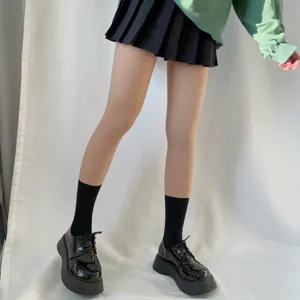 Detail shot of fake translucent nude pantyhose paired with black socks and platform shoes.