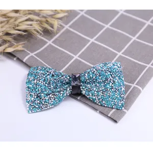 Close-up of a sparkling blue rhinestone bow tie with a center crystal detail on plaid cloth.