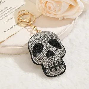 Detail view of a sparkling rhinestone skull keychain, featuring metallic gold clasp and diamonds.