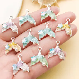 Close-up of gradient enamel mermaid tail alloy charms with pearl and rhinestones for DIY jewelry.