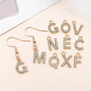 Primo piano di ciondoli lettere strass oro KC e orecchini per creazione gioielli fai da te.