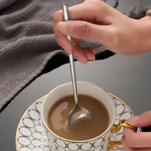 Lungo cucchiaio da caffè in acciaio inossidabile con elegante tazza in ceramica per dolci.