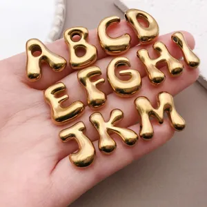 Gros plan détaillé de charms lettre dorés, perles alphabet en acier inoxydable pour bijoux.