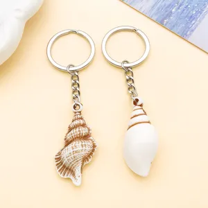 Close up view of acrylic seashell keychain pendants with detailed white and brown patterns.