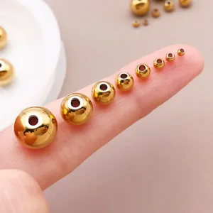 Perles d'espacement en acier inoxydable doré sur le doigt, idéales pour les bijoux DIY.