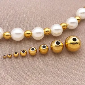 Vue détaillée de perles d'espacement en acier inoxydable doré et perles blanches pour bijoux.