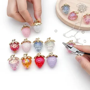 Closeup of colorful acrylic resin strawberry charms with gold caps for DIY jewelry making.
