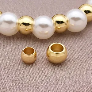 Close-up of DIY gold plated metal beads and white pearl spacer components for custom jewelry.