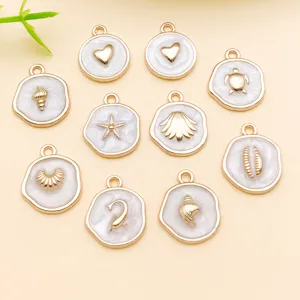 Détails en gros plan des pendentifs breloques en alliage nacré blanc motif mer et coquillages.