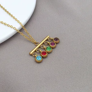 Gedetailleerd uitzicht op de gouden roestvrijstalen ketting met gekleurde steenhangers.