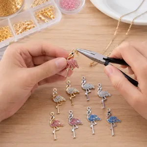 Gros plan détaillé de la fabrication artisanale de charms flamants roses en strass métal.