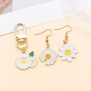 Detailopname van witte madeliefje geëmailleerd legering sleutelhanger en oorbellen sieraden set.