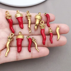Vue détaillée de petits pendentifs piment en émail rouge et or pour bijoux DIY.
