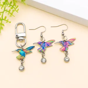 Close-up detail of colorful enamel hummingbird charms and crystal earrings set for women.