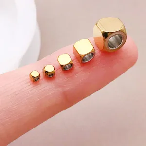 Primo piano dettagliato di perline distanziatrici quadrate in acciaio inossidabile dorato.