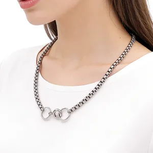 Close-up of a silver box chain necklace featuring an interlocking multi-ring front clasp.