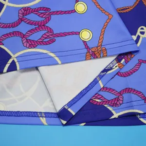 Close-up detail of women's dress hem featuring blue fabric with stylish rope chain print.