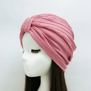 Close-up detail van de roze gekreukte tulband hoofddoek met fijne plooitextuur en knoop.