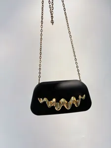 Matte black clutch bag with gold chain and metal wave detail for evening dress events.