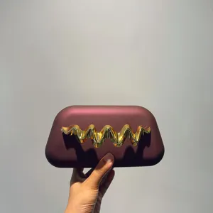 Elegant matte box clutch evening bag with striking gold wave metal decor for formal events.
