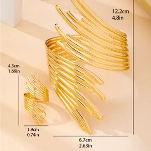 Dettaglio bracciale manchette aperto astratto dorato e anello, gioiello stile punk moderno.