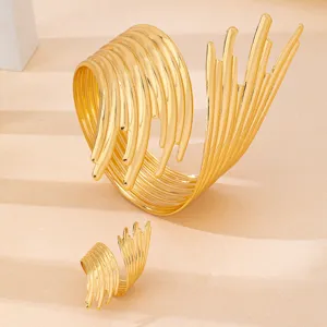 Set bracciale rigido aperto e anello dorati con dettagli di design in stile punk.