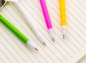 Cute colorful student ballpoint pens set with cartoon designs on lined notebook background.