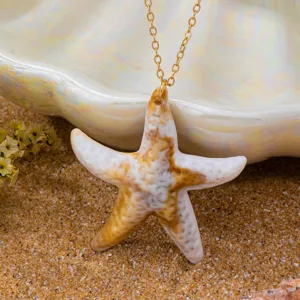 Detailaufnahme des Keramik-Seestern-Halskettenanhängers auf feinem dekorativen Strandsand.